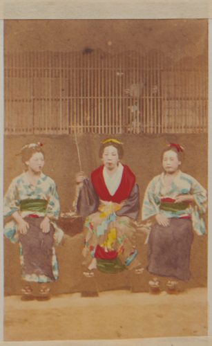 Shimooka Renjō?, ‘Ōsaka jorō (Osaka prostitutes )’/ ‘Osaka beauties’, c.1863-70. Prostitutes pose outside a brothel. A pair of hands can be seen holding the lattice behind them.